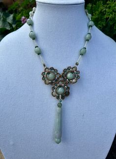 This beautifully executed necklace is made of stands are jade beads interspersed with glass beads for a visual effect. They connect in the front in a floral cluster and a jade medallion tops it off. This is a one of a kind, necklace and we think it is truly special. This floral inspired necklace from a husband and wife team that take beads, jade and present them in beautiful novel ways. It's handmade, and we procured the only one they had. Details: Button clasp. Size: Length of strand (from flow Luxury Beaded Jade Necklace, Hand-strung Round Jade Bead Necklaces, Carved Jade Round Bead Necklace, Carved Jade Bead Necklaces, Spiritual Hand-strung Jade Beaded Necklace, Jade Necklace, Floral Pendant, Beaded Statement Necklace, Jade Beads