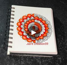 a spiral notebook with an orange and white flower on the cover, which reads jail's creations 9