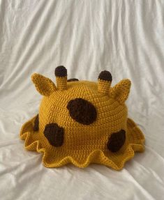 a crocheted yellow hat with black spots on it's face and ears