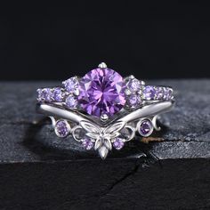 a close up of a ring with a purple stone in the center and diamonds around it