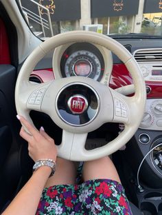 a woman is sitting in the driver's seat of a car with her hands on the steering wheel