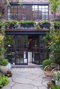 an image of a building with lots of plants on the front and side doors that are open