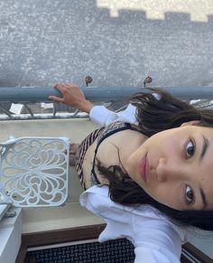 a woman is posing for the camera on a balcony with her hands behind her head