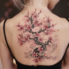 the back of a woman's neck with cherry blossom tattoos on her upper and lower back