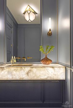 a bathroom sink with a vase on top of it and two lights above the sink