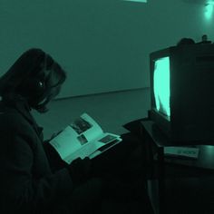 a woman sitting in front of a tv reading a book