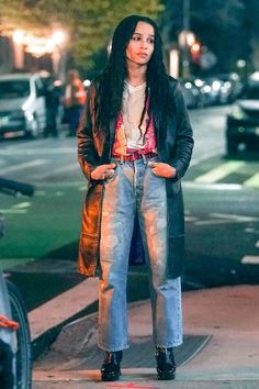 a woman with long black hair is standing on the sidewalk