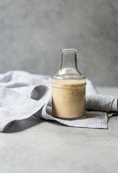 a glass bottle sitting on top of a white towel next to a gray and white cloth