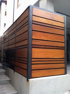 a wooden fence on the side of a building next to some concrete steps and stairs