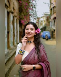 a woman in a sari standing on the side of a street talking on a cell phone