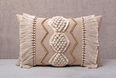 a decorative pillow with tassels on the front and back, sitting on a table