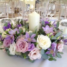 a centerpiece with purple and white flowers is on a table at a wedding reception