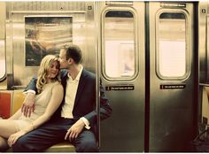 a man and woman are sitting on a subway car kissing while the train door is open