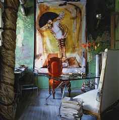 a room with a painting on the wall next to a chair and table in it