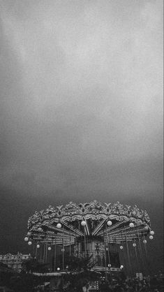 a black and white photo of a carnival ride in the rain with lots of lights