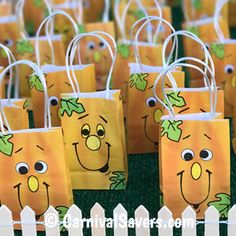 small bags with faces on them sitting in front of a white picket fence and green grass