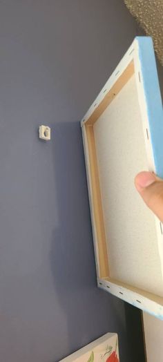 a hand is holding an open box on the wall