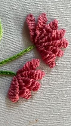 two crocheted pink flowers sitting next to each other on a white table cloth