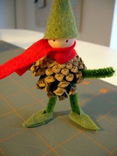 a pine cone bird with a red scarf on it's head is standing next to a pile of pine cones