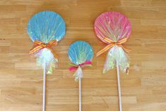 three colorful lollipops with bows on them sitting on a wooden floor next to each other