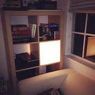 a couch sitting in front of a window next to a book shelf filled with books