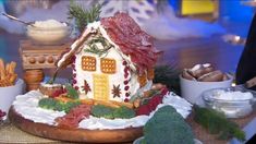 a gingerbread house is displayed on a table with other foods and condiments