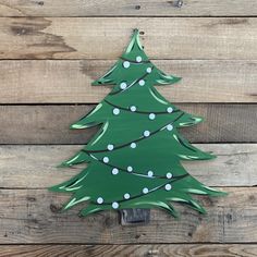 a green christmas tree with white lights on it sitting on top of a wooden wall