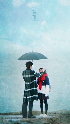 two people standing under an umbrella on the beach