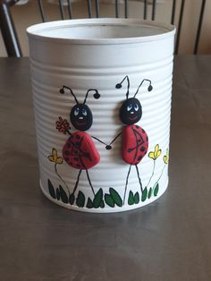 a white container with two ladybugs painted on it's sides, sitting on a table