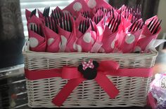 a wicker basket filled with pink and white polka dot paper utensils in front of a window