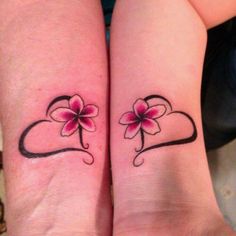 two matching tattoos with hearts and flowers on their arms, one has a pink flower in the shape of a heart