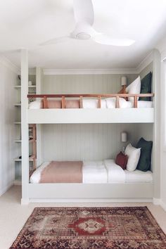 a bunk bed with two sets of beds underneath it and a rug on the floor