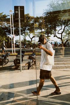 a man is walking down the street with his cell phone