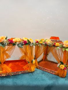 two beds covered in orange drapes with flowers on each side and one bed topped with sheer curtains