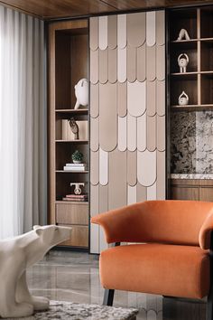 an orange chair sitting in front of a book shelf