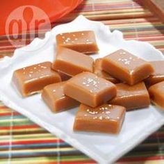 there are many pieces of caramel fudge on the white plate and colorful table cloth