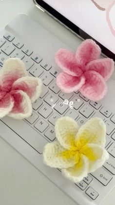 three crocheted flowers sitting on top of a computer keyboard