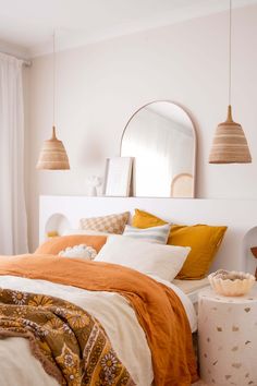 a bed with orange and white sheets in a bedroom next to a mirror on the wall