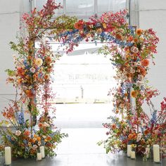 an archway decorated with flowers and candles