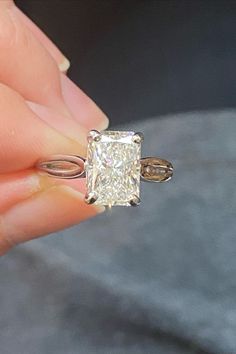 a person holding a ring with a princess cut diamond in it's middle finger