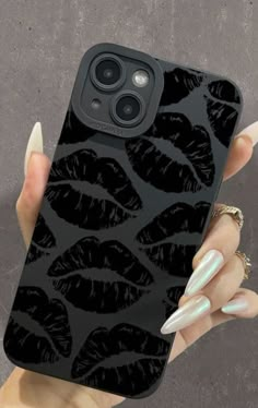 a woman's hand holding up a black phone case with white nails on it