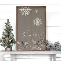 a wooden sign that says let it snow next to a christmas tree and pine cones