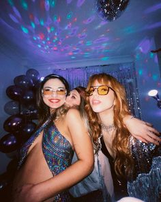 three beautiful young women standing next to each other in front of balloons and streamers