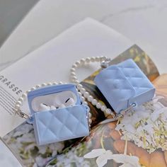 two small blue purses sitting on top of an open brochure with pearls