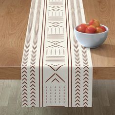 a bowl of fruit sitting on top of a table next to a white and brown table runner