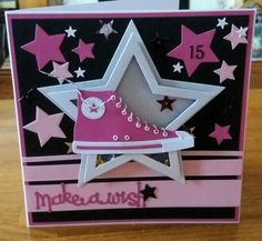 a card with a pink shoe and stars on the bottom, in front of a wooden table