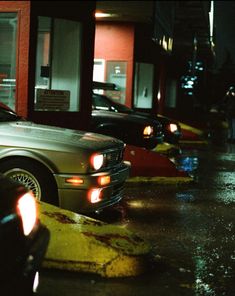 the cars are parked on the side of the road in the rain at night time