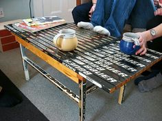 two people sitting on a couch next to a table with some cans and cups on it