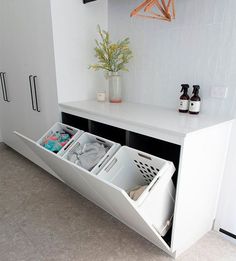 a white cabinet with two open drawers and clothes in the bottom drawer next to it