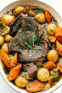 pot roast with potatoes, carrots and parsley in a white bowl on a table